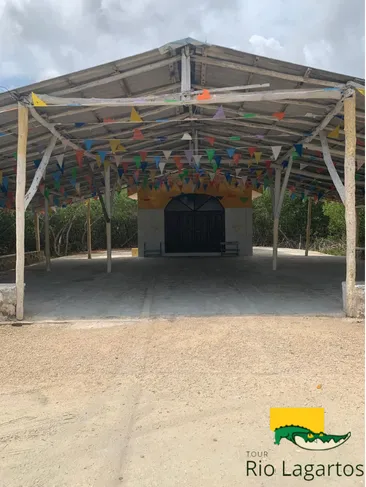 entrada de la capilla de la virgen de guadalupe en rio lagartos, adornada ocn bandera de colores y en medio del manglar
