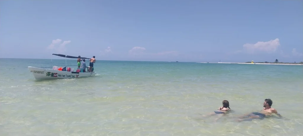 Excursión en lancha por la Biósfera de Ría Lagartos, con nuestro barco anclado mientras los turistas nadan y se relajan en las aguas cristalinas.