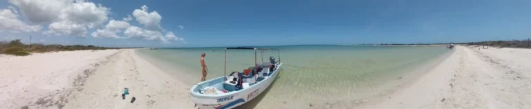 Breathtaking panoramic view of a secluded beach in the Rio Lagartos beach Biosphere, featuring our tour boat resting in the calm, crystal-clear turquoise waters.