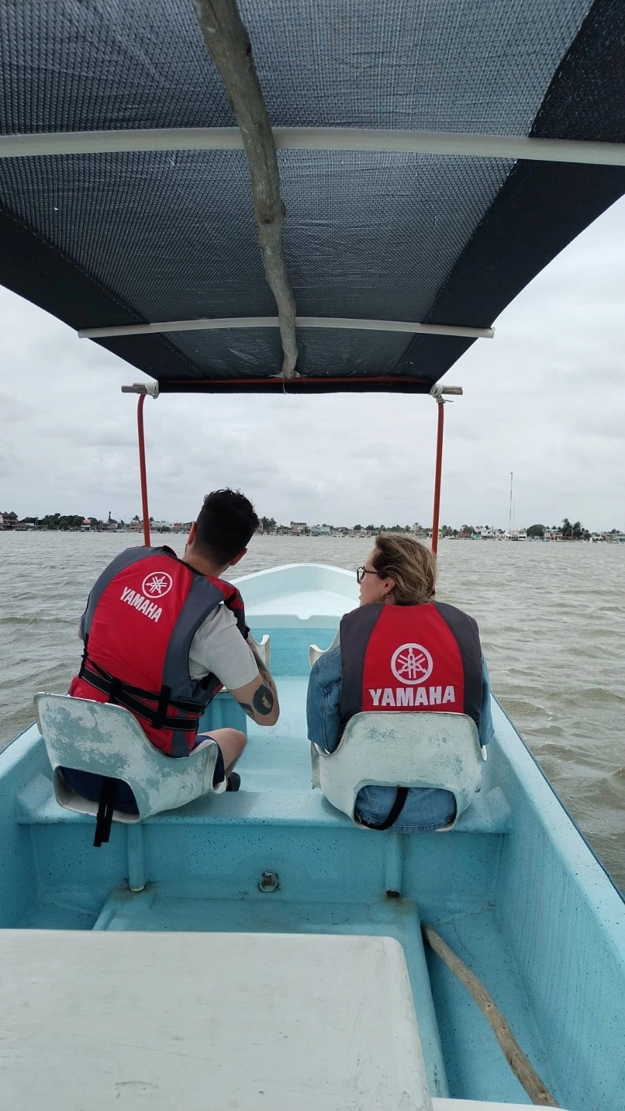 A couple wearing life jackets on a guided boat tour, looking out at the shoreline of the Rio Lagartos fishing village in Yucatan, Mexico.
