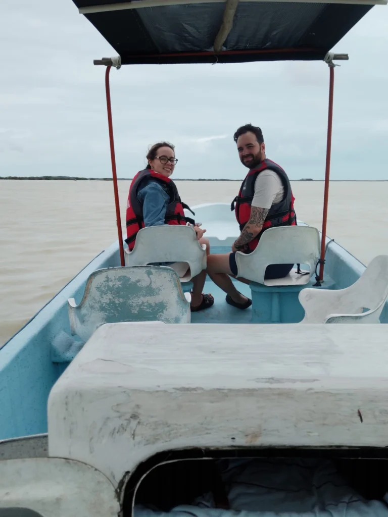 A happy young couple smiling at the camera while enjoying a safe and scenic boat tour in Rio Lagartos, wearing life jackets on their Yucatan adventure. the best rio lagartos boat tour for couples