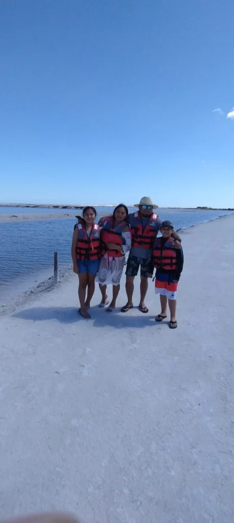 Familia feliz con niños, usando chalecos salvavidas, posando para una foto en las salinas de Las Coloradas durante su tour en lancha por Río Lagartos.
