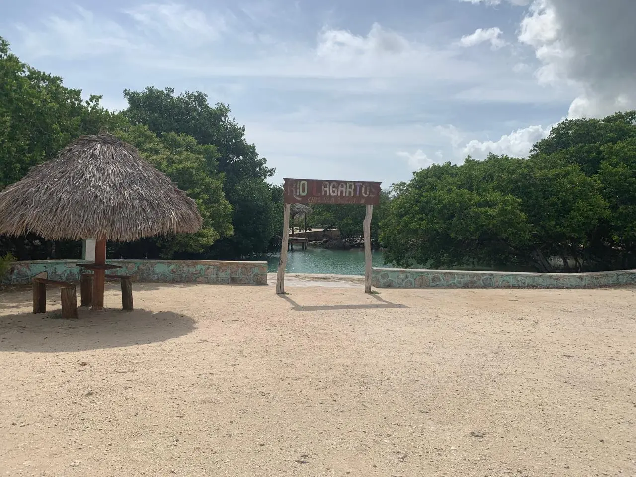 Chiquilá Río Lagartos: el ojo de agua que debes conocer en Yucatán 2 Entrada al balneario natural Chiquilá en Río Lagartos, con una palapa de paja a la izquierda y un letrero de bienvenida de madera sobre el acceso al ojo de agua.
