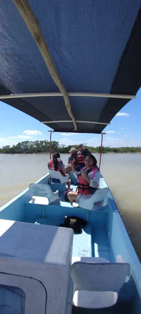 Grupo de turistas sonriendo y saludando desde una lancha durante un tour guiado por la Reserva de la Biósfera Ría Lagartos, Yucatán.