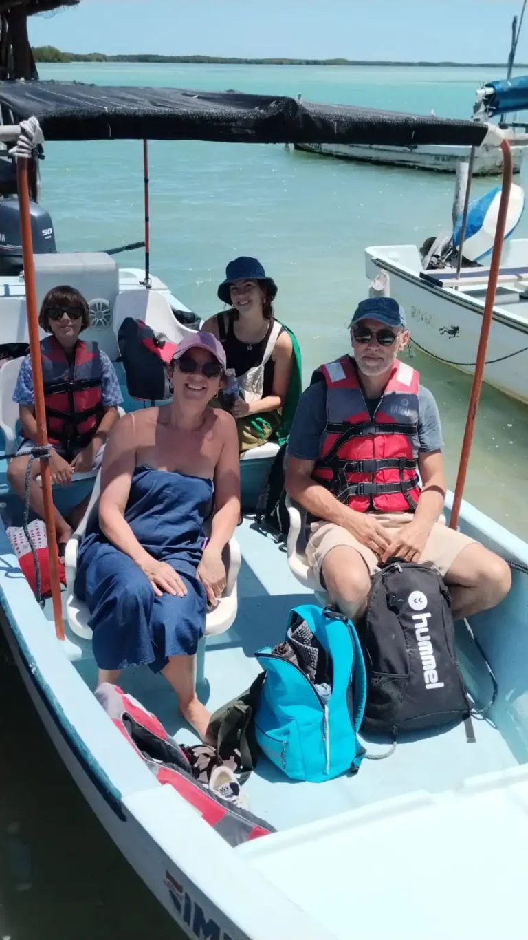 Familia sonriendo en un tour en lancha por Río Lagartos, Yucatán. Los padres y sus dos hijos llevan chalecos salvavidas, disfrutando de un paseo seguro por la biósfera.