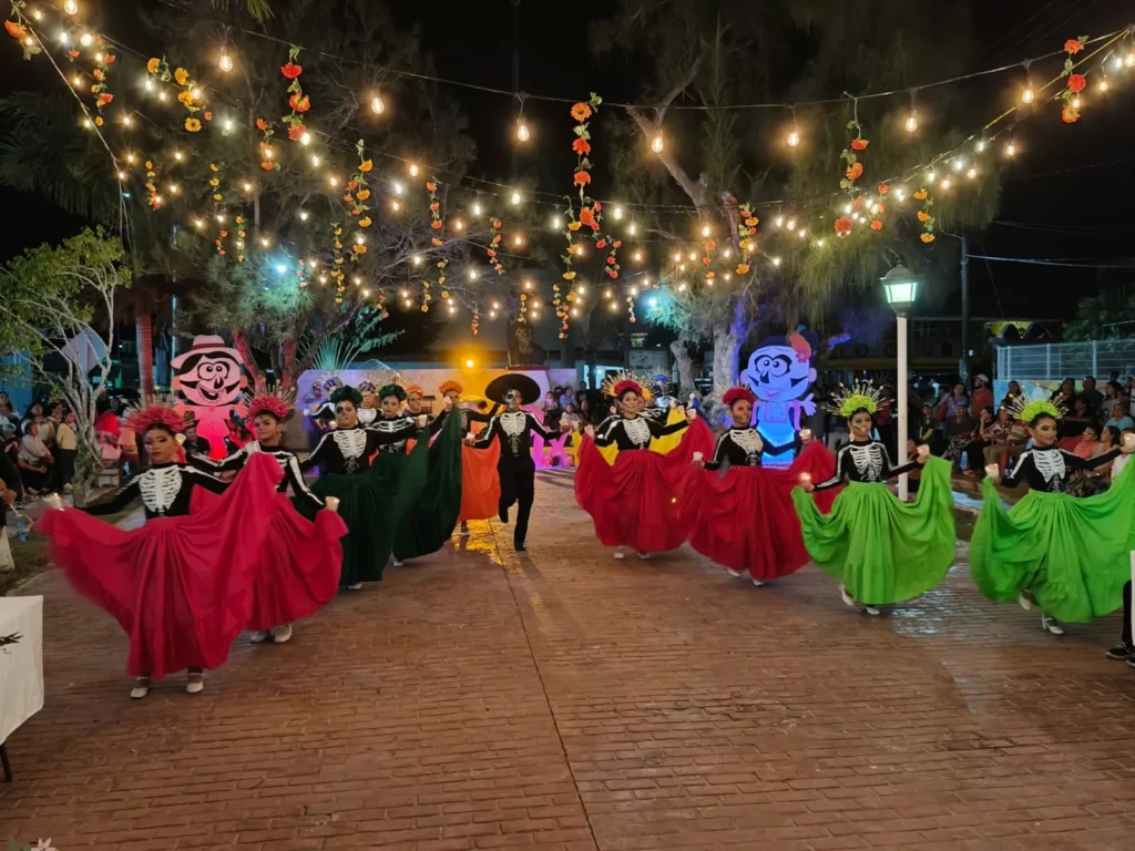 Grupo de ballet folclórico con trajes de catrinas y calaveras danzando en el parque de Río Lagartos durante el evento cultural del Festival de Ánimas en río lagartos