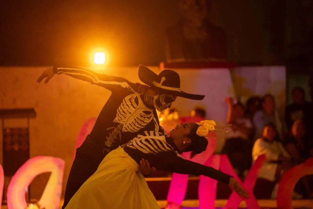 Una pareja de bailarines vestidos con trajes de esqueleto y catrines realizan un paso de baile de jarana yucateca durante el evento cultural del Festival de Ánimas en Río Lagartos.