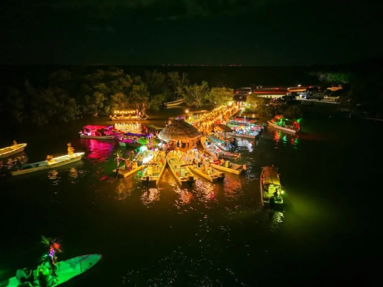 Vista aérea nocturna del muelle Chiquilá en Río Lagartos, con decenas de lanchas iluminadas y decoradas, listas para iniciar el Paseo de Pixanes del Festival de Ánimas.