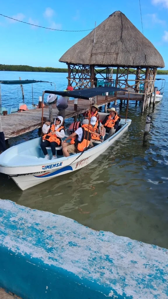 Group of international tourists wearing orange life jackets sitting on a boat at the dock preparing for Rio Lagartos excursions and rio lagartos adventures