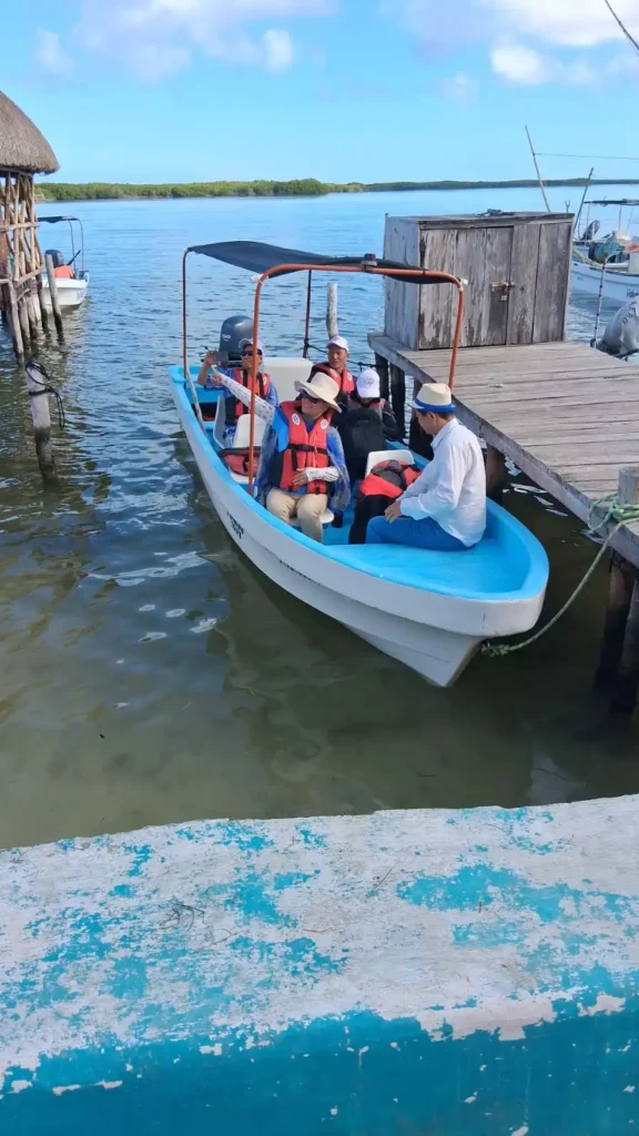 International tourists sitting comfortably on a safe boat tour with life jackets at the Rio Lagartos dock.