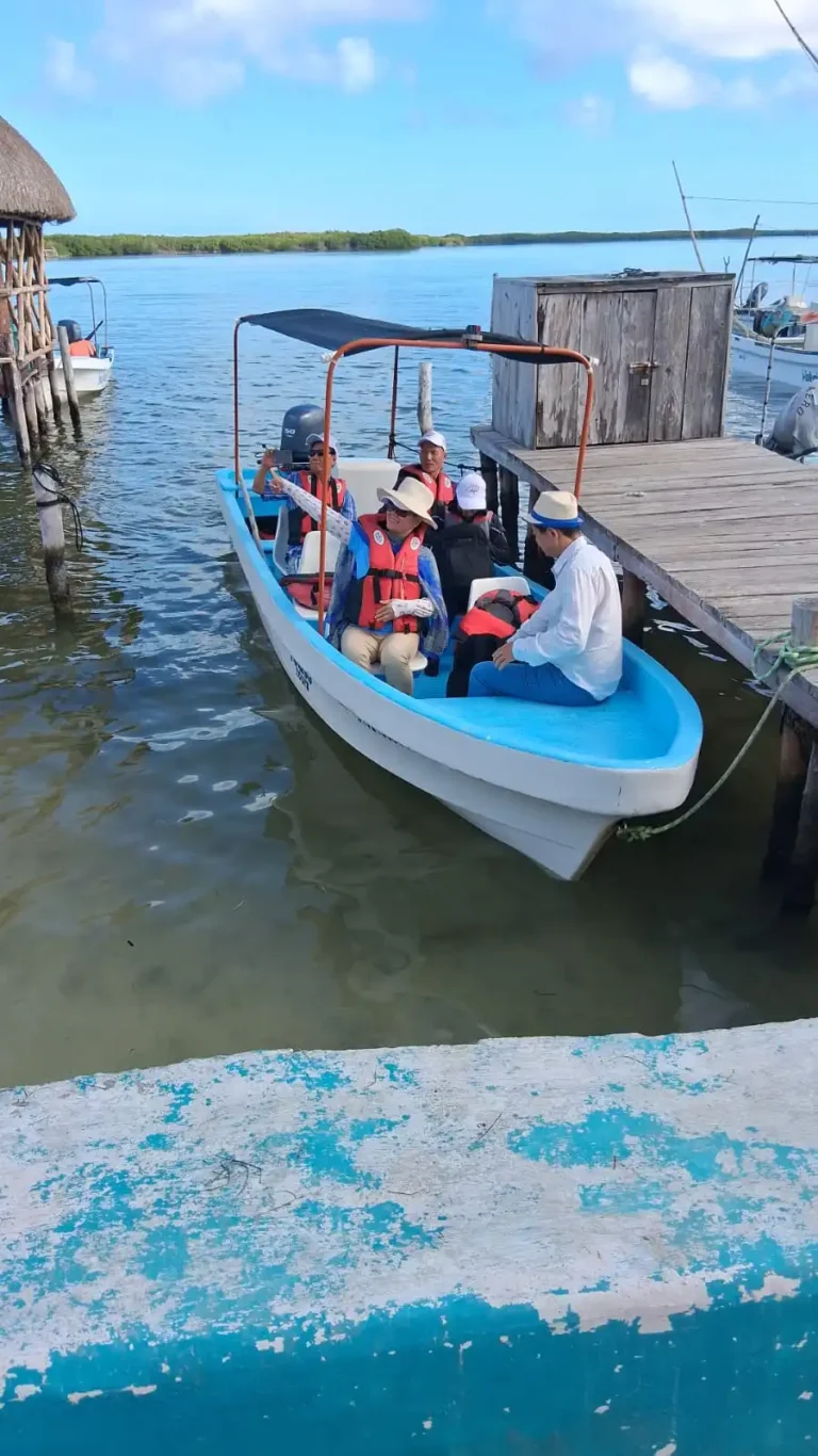 International tourists sitting comfortably on a safe tour boat with life jackets at the Rio Lagartos dock.