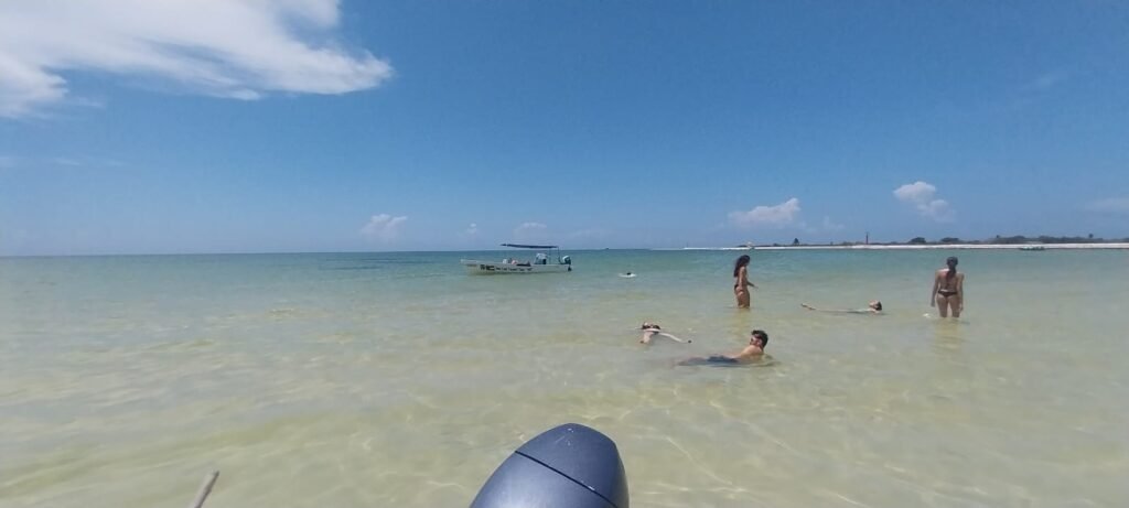 Turistas nadando en playas casi vírgenes de aguas cristalinas, una parada exclusiva que incluye el tour Río Lagartos el avistamiento de flamingos y relajación.