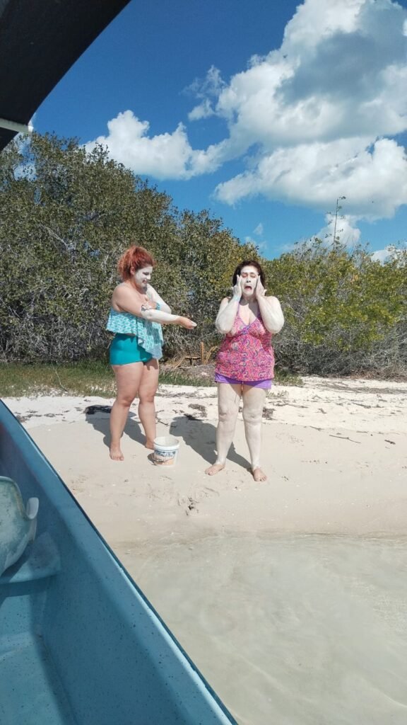 Tourists applying white medicinal mud during a private mayan mud bath rio lagartos experience on a sunny beach