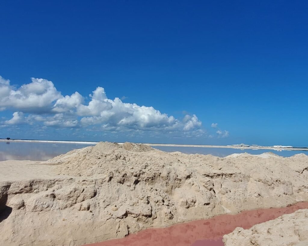 Rio Lagartos Travel Guide 2026: The Perfect Full Day Itinerary Beyond the Flamingos 14 A high-contrast view of the Las Coloradas pink lakes showing bright pink water canals, large mounds of industrial salt, and a deep blue sky in Yucatan.