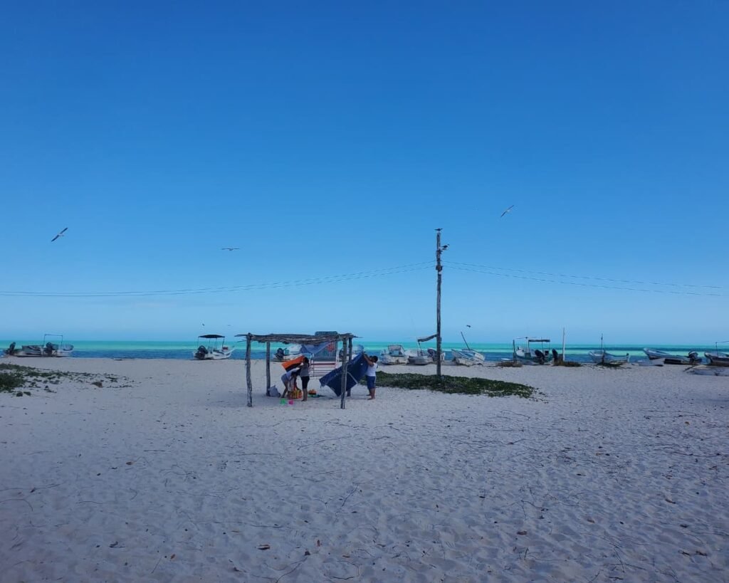 Rio Lagartos Travel Guide 2026: The Perfect Full Day Itinerary Beyond the Flamingos 16 A family setting up shade on a white sand beach from the Rio Lagartos Day Trip Guide, showcasing popular Things to Do in Rio Lagartos during a One Day in Rio Lagartos Full Day Itinerary.